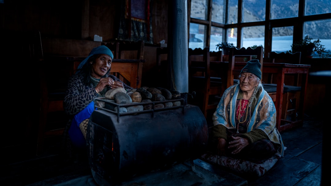 Two elderly people sitting by a stove